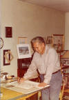 George Ahgupuk working at his art desk
